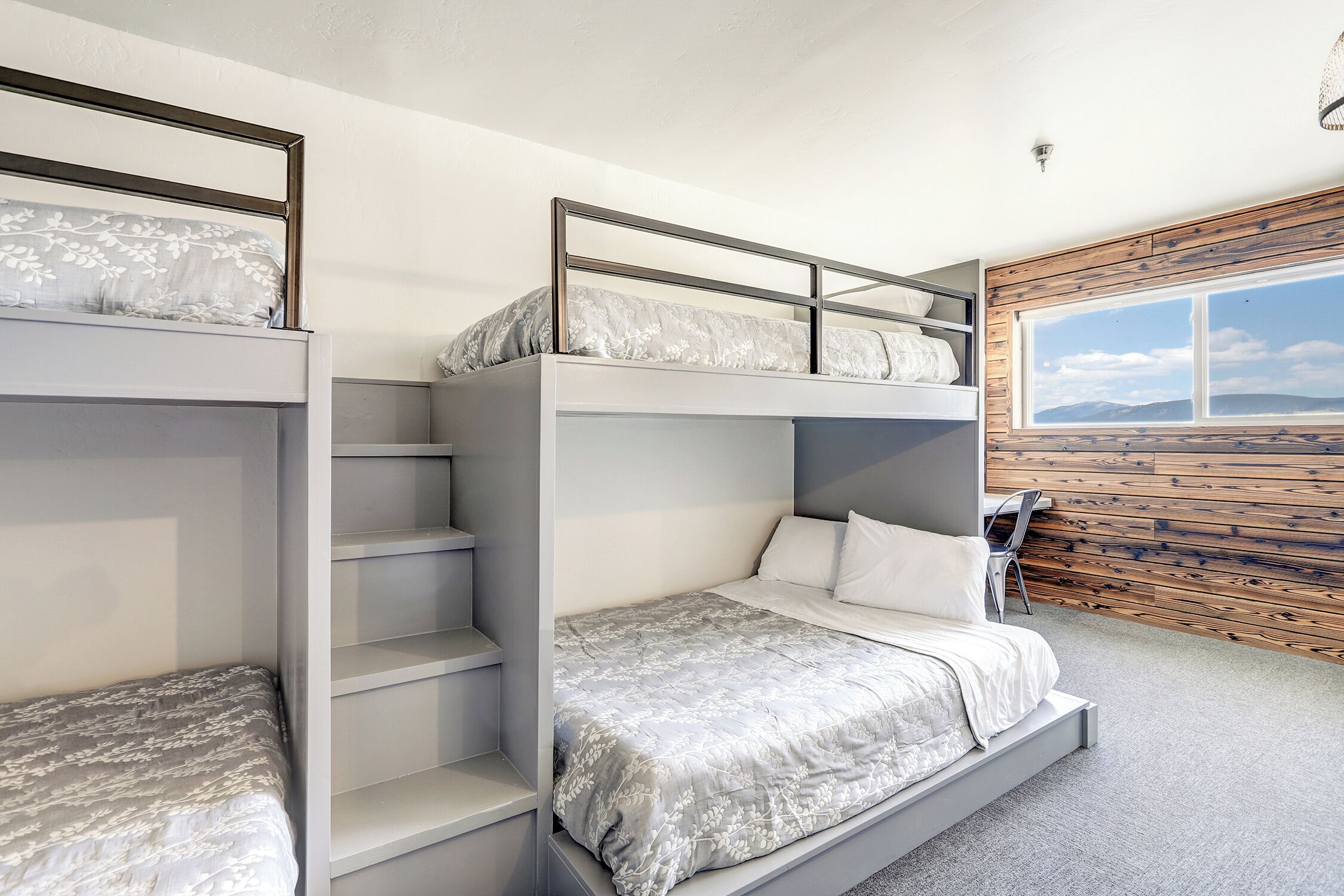 A bunk bed room with a view of the mountains through a large window.