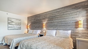 Ein Hotelzimmer mit zwei Betten, einem Holz-Kopfteil, Wandleuchten und einem gerahmten Bild.