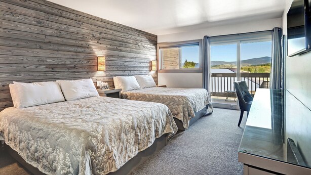 Ein Schlafzimmer mit zwei Betten, einem Fernseher und einem Balkon mit Bergblick.