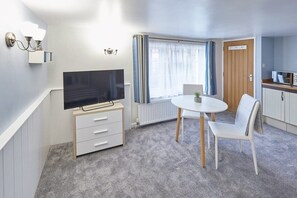 A compact living space with a television, a small dining table, and a chair.