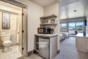 Una habitación de hotel compacta con baño, kitchenette y un balcón con vistas.