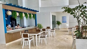A modern indoor dining area with a counter, white chairs, and potted plants.