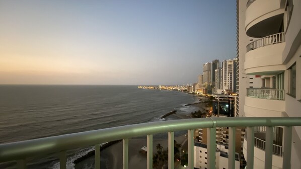 A coastal cityscape with high-rise buildings, a beach, and a clear sky.