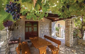 An outdoor seating area with stone walls, a wooden table, and benches. - Holiday House Marina (Sveti Lovrec)