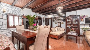 A rustic living room with a wooden dining table, a sofa, and a television. - Holiday House Marina (Sveti Lovrec)
