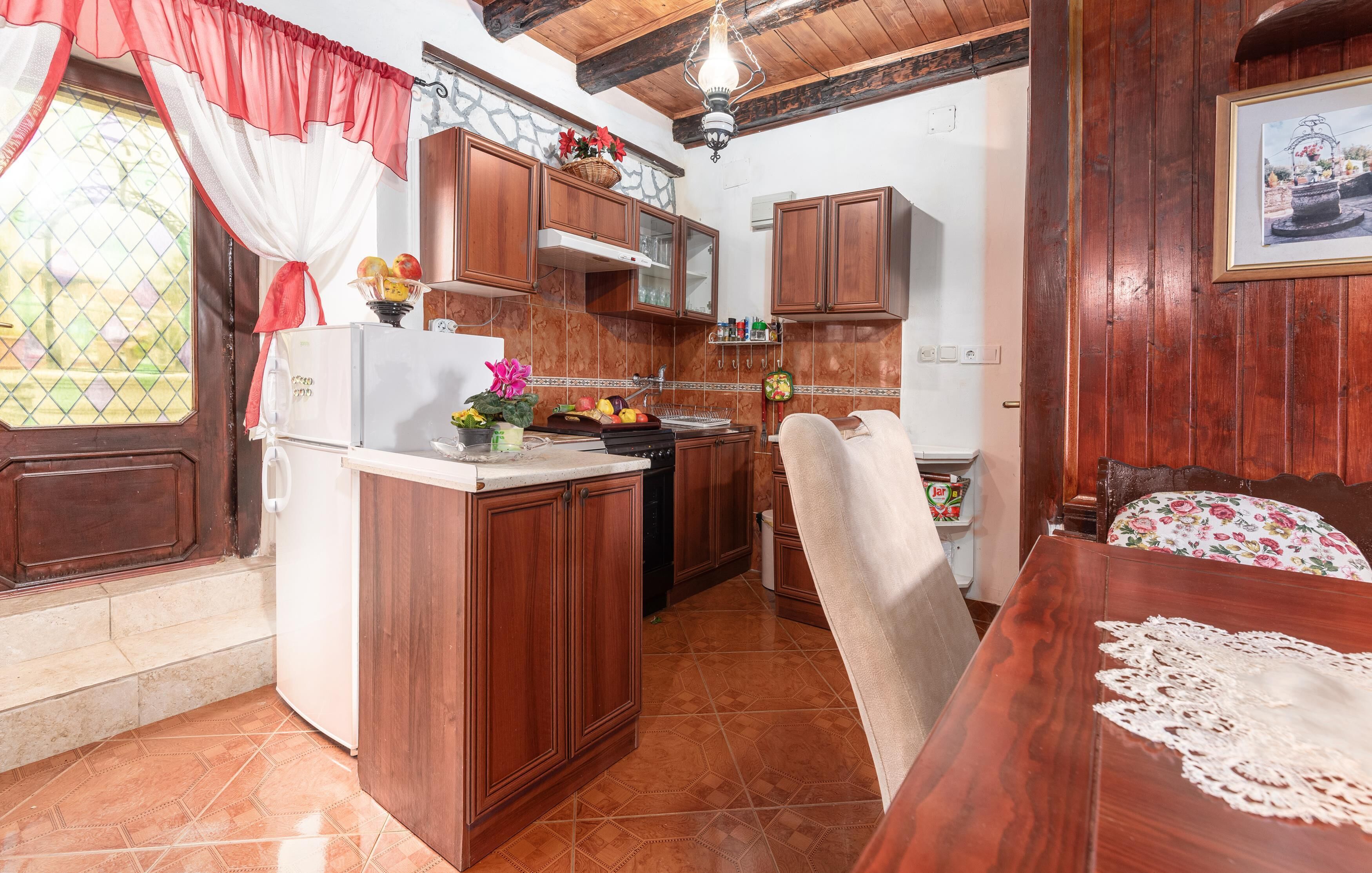 A kitchen with wooden cabinets, a refrigerator, a sink, and a dining table with chairs.