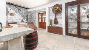 A stone-floored interior with a staircase, a wooden door, a glass cabinet with antiques, and a stone barrel. - Holiday House Marina (Sveti Lovrec)