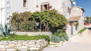 A traditional stone building with a white facade, a stone wall in front, and a metal gate with a number sign. - Holiday House Marina (Sveti Lovrec)