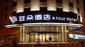 Un hôtel avec une enseigne bien visible portant l’inscription « Atour Hotel » et un logo au-dessus de l’entrée.