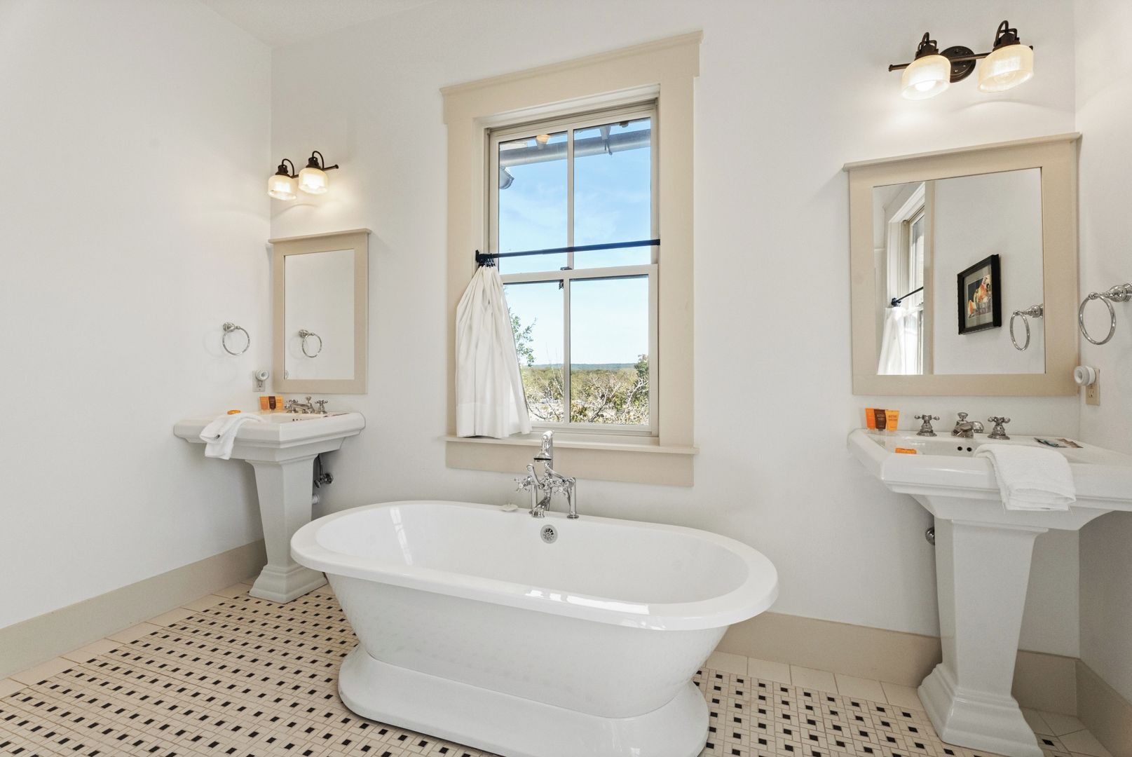 Une salle de bain avec une baignoire sur pieds, deux lavabos et une grande fenêtre.