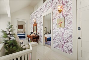 Un pasillo con una escalera que lleva a un dormitorio. Hay un árbol de Navidad y un espejo en la pared.