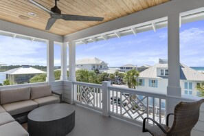 A covered outdoor area with a ceiling fan, a round table, a sofa, and a wicker chair.