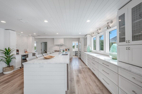 A spacious kitchen with a central island, white cabinetry, and large windows providing natural light.