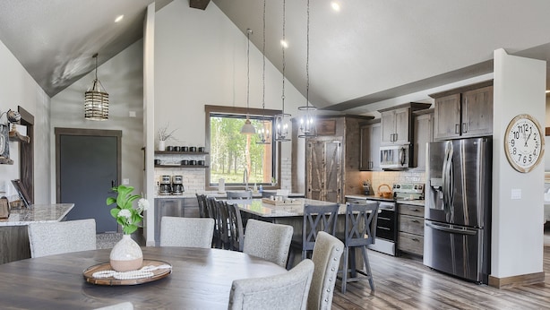 A spacious kitchen with a large island, stainless steel appliances, and a dining area with a round table and chairs. - Stunning 3700+ Sq. Ft Lodge w/ Firepit, Hot Tub, Large Garage - Paved! (Lead)