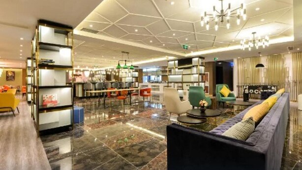 A modern hotel lobby with a marble floor, a sofa with cushions, a bookshelf, and a chandelier. - Atour Hotel Qinhuangdao Beidaihe Zhoudun (Qinhuangdao)
