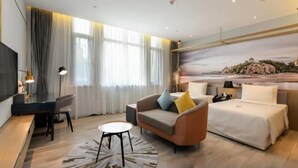 A modern hotel room with a bed, a sofa, a desk, and a TV. - Atour Hotel Qinhuangdao Beidaihe Zhoudun (Qinhuangdao)