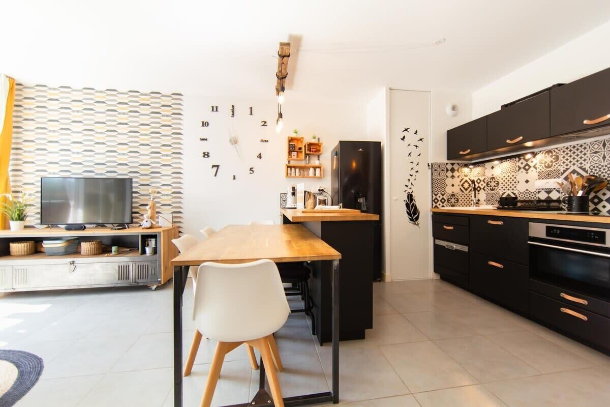 Eine moderne Küche mit einem Holztisch, schwarzen Schränken und einem eingebauten Backofen.