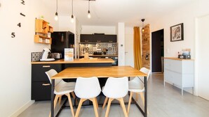 A modern kitchen with a central island, white chairs, and a wooden table. - Appartment Christine in Lège city for 5 persons (Lège-Cap-Ferret)