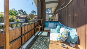 A cozy balcony with a wooden fence, a cushioned seating area, and a patterned rug. - Appartment Christine in Lège city for 5 persons (Lège-Cap-Ferret)