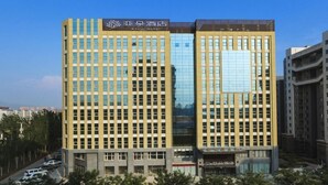 Un hotel moderno con fachada de diseño geométrico, ventanas amplias y un letrero llamativo en la parte superior.
