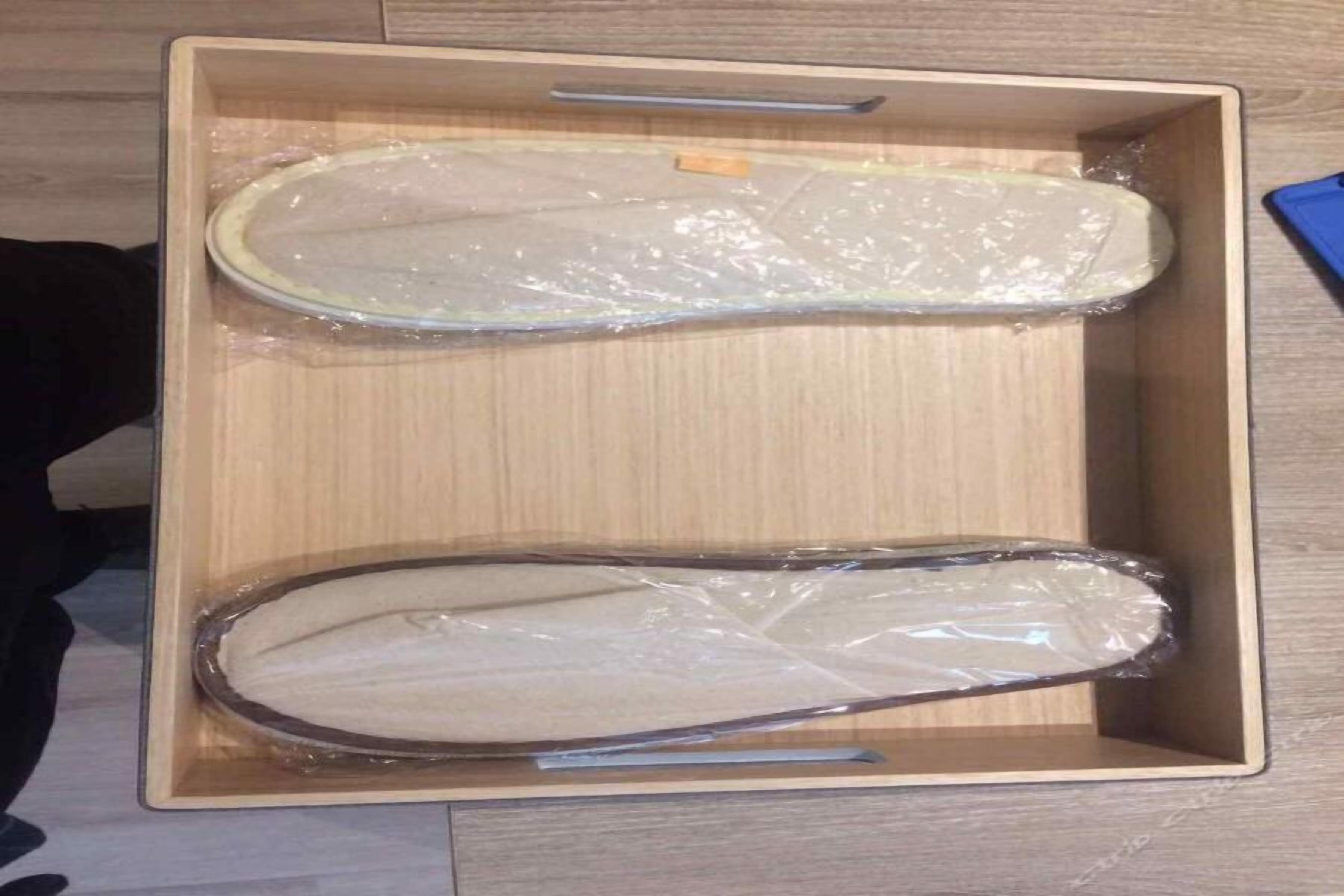 Una scatola di legno con due oggetti avvolti nella plastica.