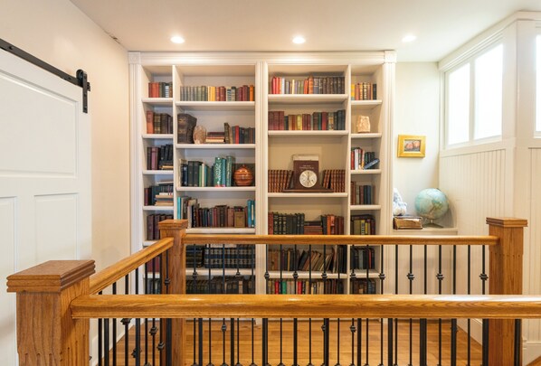 Eine Bibliothek mit Bücherregalen, einer Holztreppe und einem Globus.