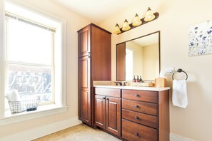 A bathroom with a window, a sink, a mirror, and a towel rack.