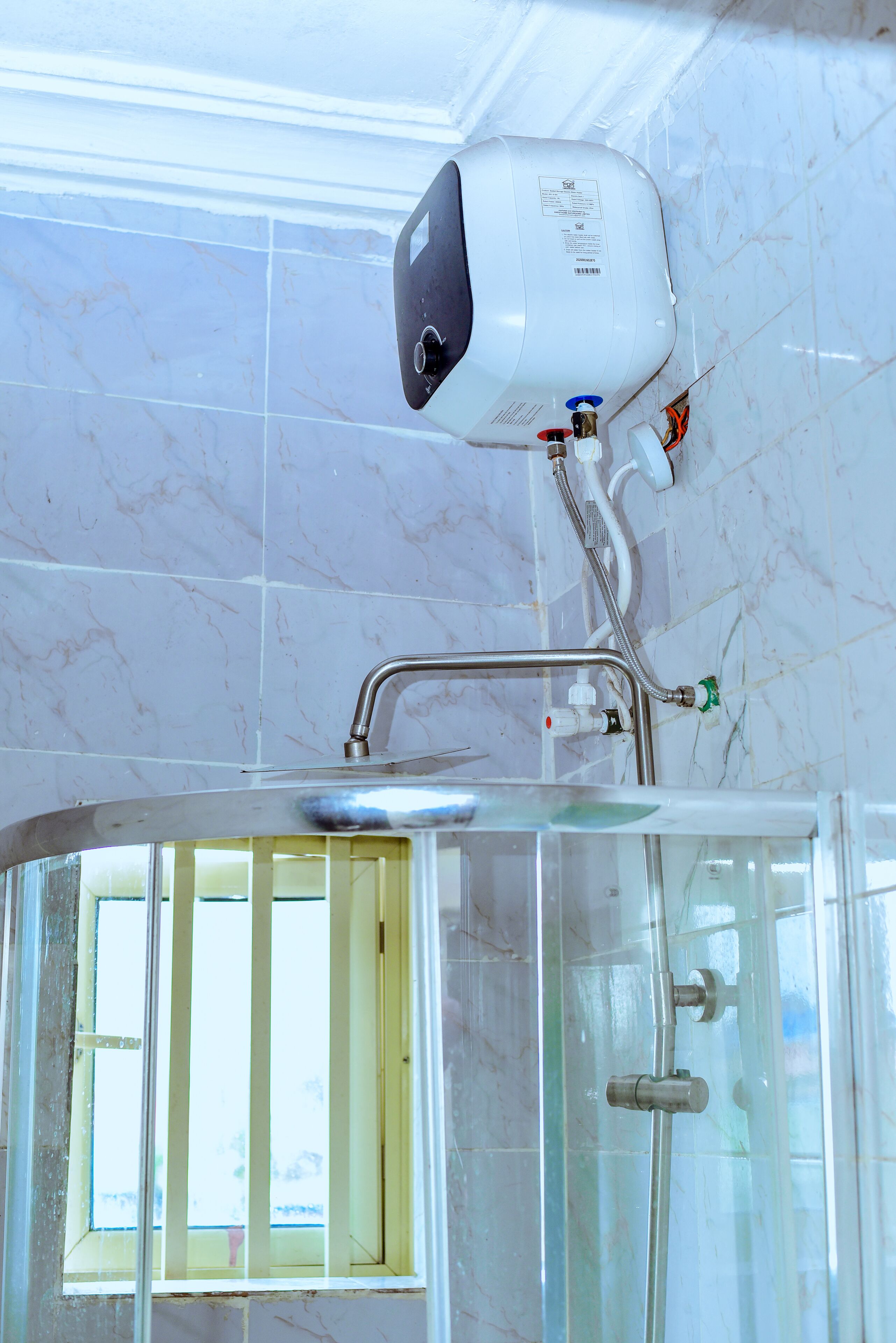 A bathroom with a glass shower enclosure, a handheld showerhead, and a wall-mounted faucet.