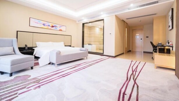 Une chambre d’hôtel moderne dotée d’un grand lit, d’un coin salon et d’un bureau.