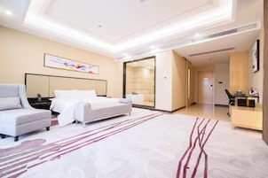 A modern hotel room with a large bed, a seating area, and a desk.