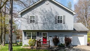 Una casa a due piani con un portico, una porta rossa e un garage.
