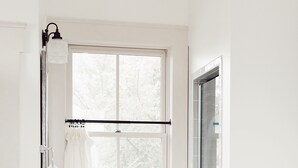 Un baño con un lavamanos blanco, una ventana y una zona de ducha.