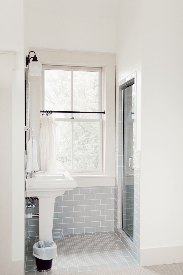 A bathroom with a white sink, a window, and a shower area.