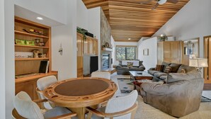A spacious living area with a wooden dining table and chairs, a comfortable sofa, and a kitchen with wooden cabinets and a stone accent wall.