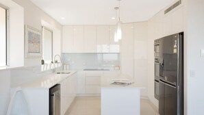 Eine moderne Küche mit weißen Schränken, einem eingebauten Ofen und einem Edelstahl-Kühlschrank.