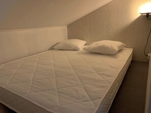 Cozy retreat with a single bed, quilted mattress, and two pillows.