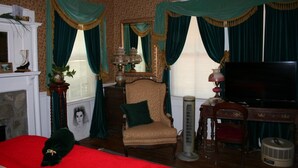 A room with a fireplace, a large mirror, a television, and a chair. - Country Manor - Lower floor (Henderson)