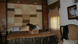 A bedroom with a large bed, a nightstand, a chair, and a wall-mounted picture. - Country Manor - Lower floor (Henderson)