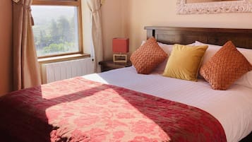 Un dormitorio con cama, mesita de noche, espejo y ventana con cortinas.