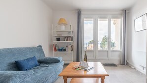 A living room with a blue sofa, a wooden coffee table, and a bookshelf. - L'Amiral - Plage - Parking (La Bernerie-en-Retz)