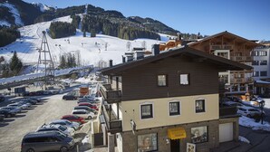 A two-story building with a ski lift in the background. - TownHouse Appartements (Saalbach-Hinterglemm)