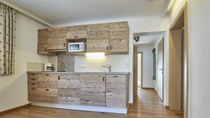 A modern kitchen with wooden cabinetry, a built-in microwave, and a stainless steel sink. - TownHouse Appartements (Saalbach-Hinterglemm)