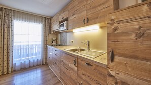 A kitchen with wooden cabinets, a stainless steel sink, and a microwave. - TownHouse Appartements (Saalbach-Hinterglemm)