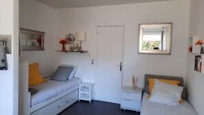 A compact bedroom with a single bed, a nightstand, a dresser, and a small table with a lamp. - Studio port arcachon (Arcachon)