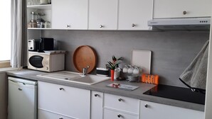 A compact kitchen with white cabinets, a microwave, a toaster, and a sink. - Studio port arcachon (Arcachon)