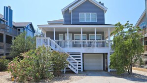 Une maison à deux étages avec un balcon, un garage et un escalier menant à l’entrée.