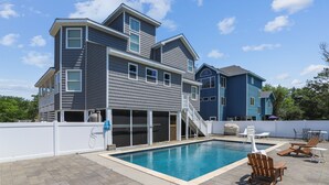 Une maison à deux étages dotée d’une piscine, d’un espace extérieur aménagé et d’un patio couvert.