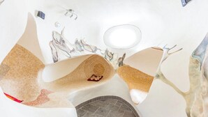 Ein Badezimmer mit einem einzigartigen Design, das ein freistehendes Waschbecken, einen Spiegel und einen Handtuchhalter zeigt.
