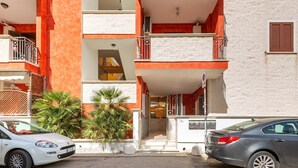 A multi-story building with balconies, a car parked in front, and a palm tree. - 1990 Appartamento Azzurra (Gallipoli)