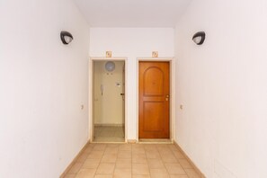 A hallway with two doors, one with a light fixture above it and the other with a number sign above it.
